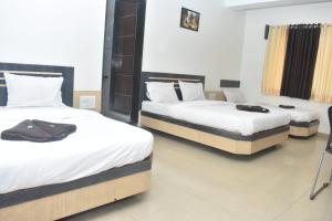 a couple of beds in a room at HOTEL SAI VISHVA KARMA in Shirdi