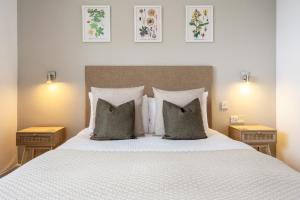 een slaapkamer met een wit bed met kussens en 2 tafels bij Inn For All Seasons in Redruth