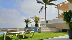 twee stoelen en een tafel op een gazon met palmbomen bij Apartment Fuerte in Corralejo