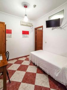een slaapkamer met een bed en een geruite vloer bij Pension Hidalgo 1 in Utrera