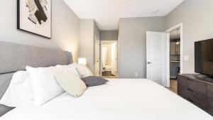 Schlafzimmer mit einem großen weißen Bett und einem Flachbild-TV in der Unterkunft Landing Modern Apartment with Amazing Amenities (ID8112X15) in Chapel Hill