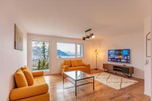 a living room with a couch and a tv at Le toit de Chardonne - Entre Alpes et lac Léman in Chardonne