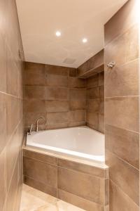 a bath tub in a bathroom with brown tiles at Le toit de Chardonne - Entre Alpes et lac Léman in Chardonne