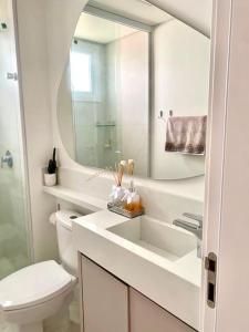 een badkamer met een toilet, een wastafel en een spiegel bij Apto em Navegantes/Gravatá in Navegantes