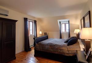 a bedroom with a bed and two windows at Chalet des bouleaux in Nominingue
