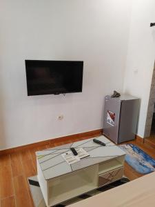 LES 9 PLURIELLES - Studio 5 في Kpalimé: غرفة معيشة مع طاولة وتلفزيون على الحائط