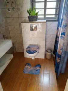 a bathroom with a toilet on a wooden floor at LES 9 PLURIELLES - Studio 5 in Palimé