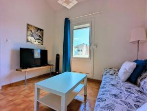 - un salon avec un canapé, une télévision et une table dans l'établissement Appartement T4/parking privé/wifi/50m de la plage, au Cap d'Agde