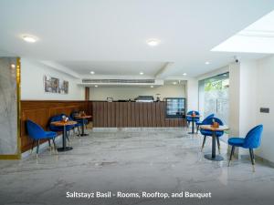 a waiting room with blue chairs and tables at Saltstayz Basil - Near Golf Course Road & Extension Road in Gurgaon