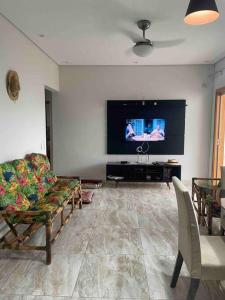 een woonkamer met een bank en een flatscreen-tv bij Pousada e Edícula in Jabuticabal