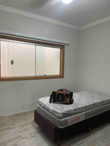 een kamer met een bed met een tas erop bij Pousada e Edícula in Jabuticabal