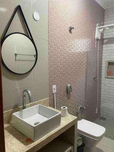 een badkamer met een wastafel, een toilet en een spiegel bij Pousada e Edícula in Jabuticabal
