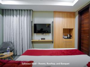 a hotel room with a bed and a television at Saltstayz Basil - Near Golf Course Road & Extension Road in Gurgaon