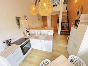 a kitchen with white cabinets and a staircase in the background at Escapade Ensoleillé in Saint-Jean-de-Monts +12 photos