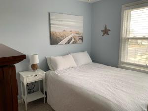 ein Schlafzimmer mit einem weißen Bett und einem Nachttisch mit einem Nachttisch in der Unterkunft Bradley Beach Cozy Retreat in Bradley Beach