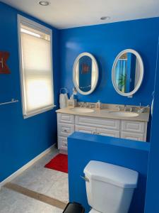 Baño azul con 2 lavabos y aseo en Bradley Beach Cozy Retreat, en Bradley Beach