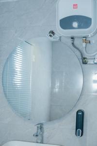 baño con espejo redondo y lavabo en Book Atelier Lux Homes! Modern Service Apartment with Amazing Balcony View en Ibadán