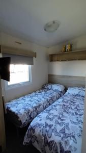 two beds in a small room with a window at Serena Little Escape, West Sands Holiday in Selsey