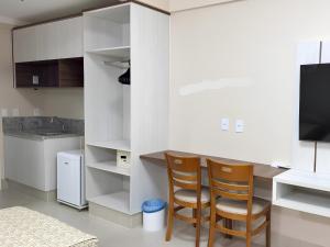 a kitchen with white cabinets and two chairs and a television at Spazzio Diroma, C - Acesso Ao Acqua Park in Caldas Novas
