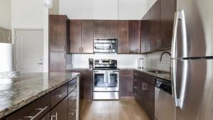 cocina con armarios de madera y nevera de acero inoxidable en Landing Modern Apartment with Amazing Amenities (ID1019X387) en Orlando