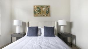 een slaapkamer met een bed met 2 tafels en 2 lampen bij Landing Modern Apartment with Amazing Amenities (ID1019X387) in Orlando
