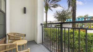 uma varanda com duas cadeiras e uma cerca e palmeiras em Landing Modern Apartment with Amazing Amenities (ID1019X387) em Orlando