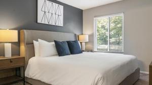 um quarto com uma cama com almofadas azuis e uma janela em Landing Modern Apartment with Amazing Amenities (ID9191X62) em Marietta