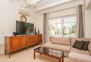 a living room with a couch and a flat screen tv at Zante Sun I - Getaway Villa! in Zakynthos