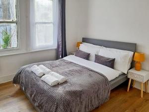 a bedroom with a large bed with towels on it at Gravesend 2 bedroom Apartment, 2 mins walk to Station in Kent
