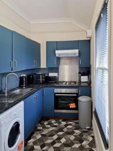 a kitchen with blue cabinets and a checkered floor at Gravesend 2 bedroom Apartment, 2 mins walk to Station in Kent