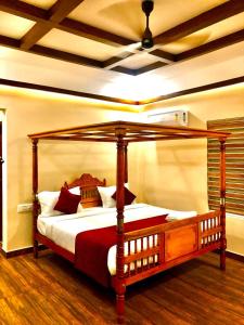 ein Schlafzimmer mit einem Himmelbett in einem Zimmer in der Unterkunft ATHIRAPPILY SREENILAYAM HERITAGE RESORt in Athirappilly