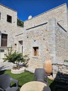 a stone building with a table and chairs in a yard at Rigas stone tower east Mani 1 in Mína