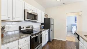 eine Küche mit weißen Schränken und einem schwarzen Kühlschrank in der Unterkunft Landing Modern Apartment with Amazing Amenities (ID8982X42) in Indianapolis