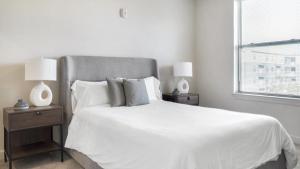 1 cama blanca con 2 mesitas de noche y 2 lámparas en Landing Modern Apartment with Amazing Amenities (ID7274X30), en Baton Rouge