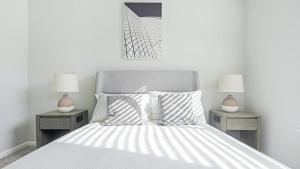 1 dormitorio blanco con 1 cama con 2 mesitas de noche y 2 lámparas en Landing Modern Apartment with Amazing Amenities (ID1170X300), en Durham