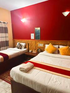 um quarto com duas camas e uma parede vermelha em Horizon Homes - Sauraha Chitwan em Sauraha