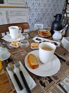 uma mesa com duas chávenas de café e uma fatia de bolo em Au charme d'antan em Féron