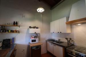 cocina con armarios blancos y microondas en Casa Azul, en Cumeada