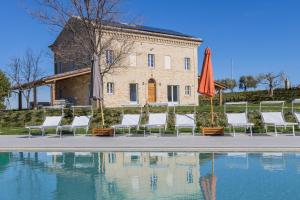 eine Gruppe Stühle und ein Sonnenschirm neben einem Pool in der Unterkunft Villa Margherita in Francavilla dʼEte