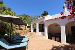 a group of chairs and an umbrella on a patio at Villa la Perla in Carvoeiro