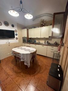 una cucina con tavolo e una cucina con armadietti bianchi di Marcelina a Roma