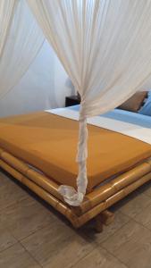 a bed with curtains on top of it at Gili Air Santay 3 in Gili Air