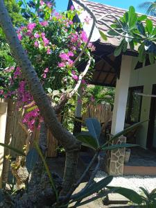 a house with pink flowers and a tree at Gili Air Santay 3 in Gili Air