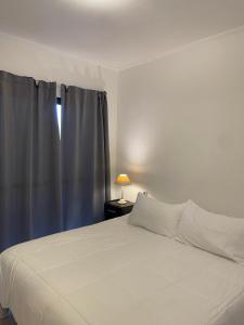 1 dormitorio con cama blanca y ventana en Departamentos Céntricos Modernos - Pagos en USD - Consultar Disponibilidad por Teléfono en Gualeguaychú