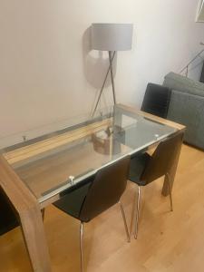 a glass table in a living room with two chairs at Entire 2 bedroom house in Hackney in London