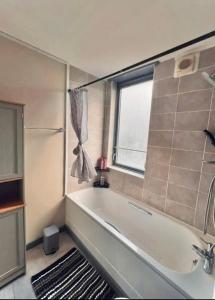a bathroom with a bath tub and a window at Entire 2 bedroom house in Hackney in London