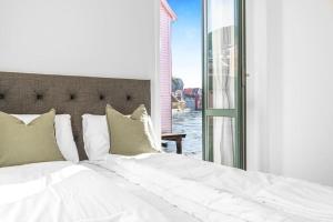 ein Bett mit weißen Laken und Kissen neben einem Fenster in der Unterkunft Seaside Apt. Catch Crabs from Your Bedroom Window! in Bergen