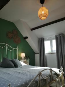 a bedroom with a bed and a green wall at La Vieille Ferme in Donnay
