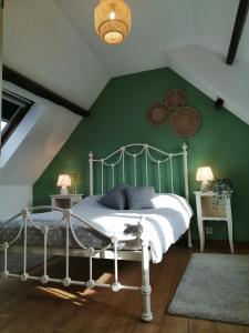 a bedroom with a white bed with a green wall at La Vieille Ferme in Donnay