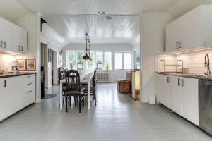 a kitchen with white cabinets and a table and chairs at Historic lakeside villa - ski, boat, relax in nature in Sunnansjö
